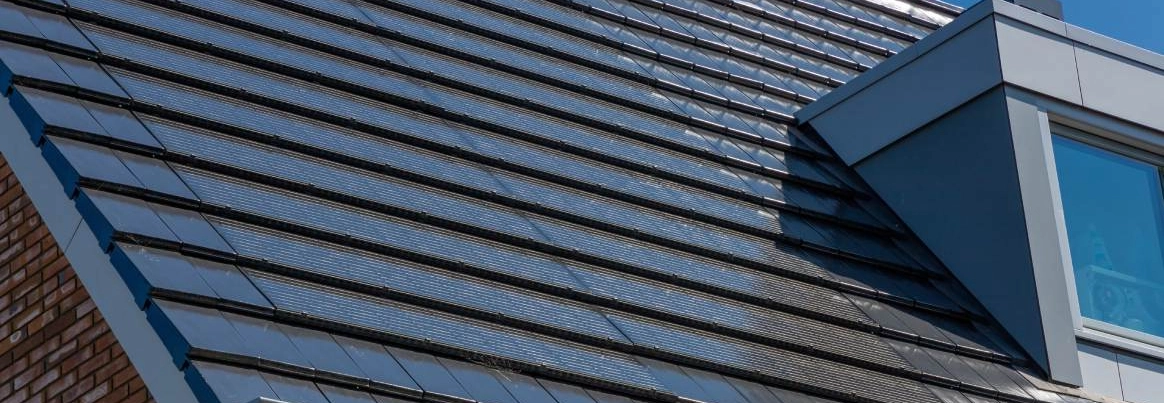 Nahaufnahme von dunklen Solardachziegeln auf einem Hausdach.